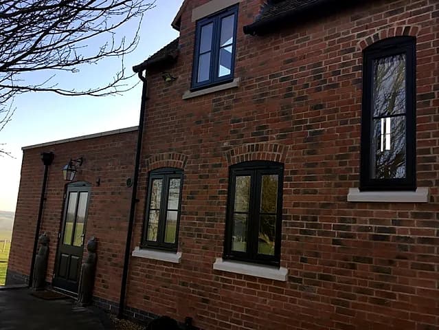 Dark timber casement windows in a red-brick period house
