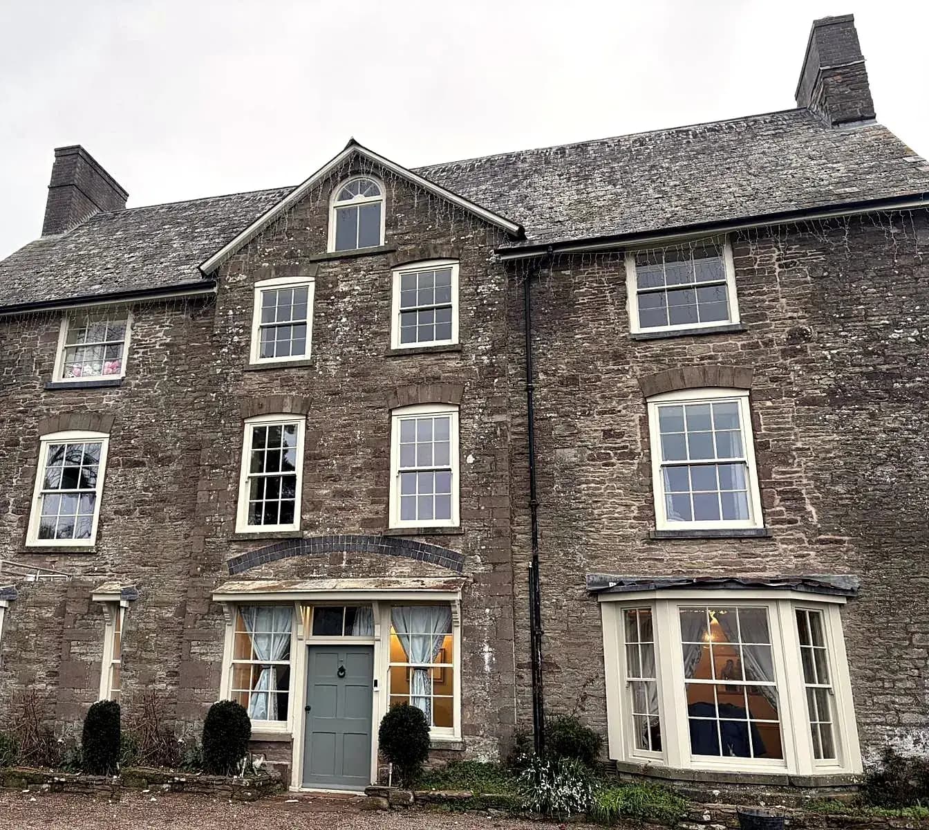Georgian stone house in Monmouthshire with newly installed cream timber sash windows across three storeys