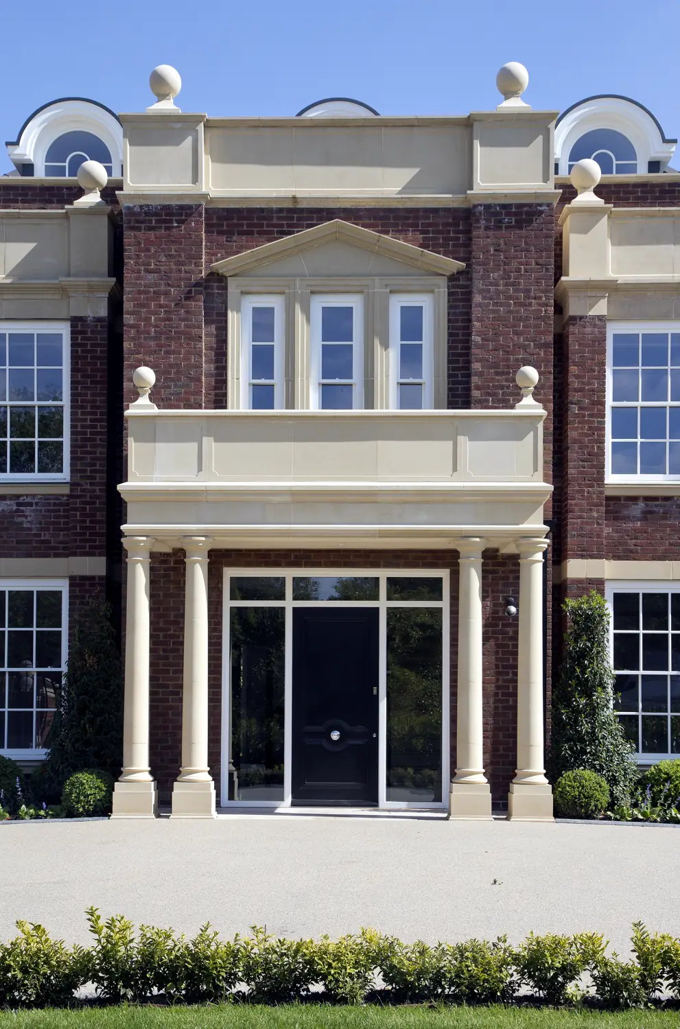 Front elevation of a grand classical Surrey home with timber sash windows, stone dressings and a columned entrance